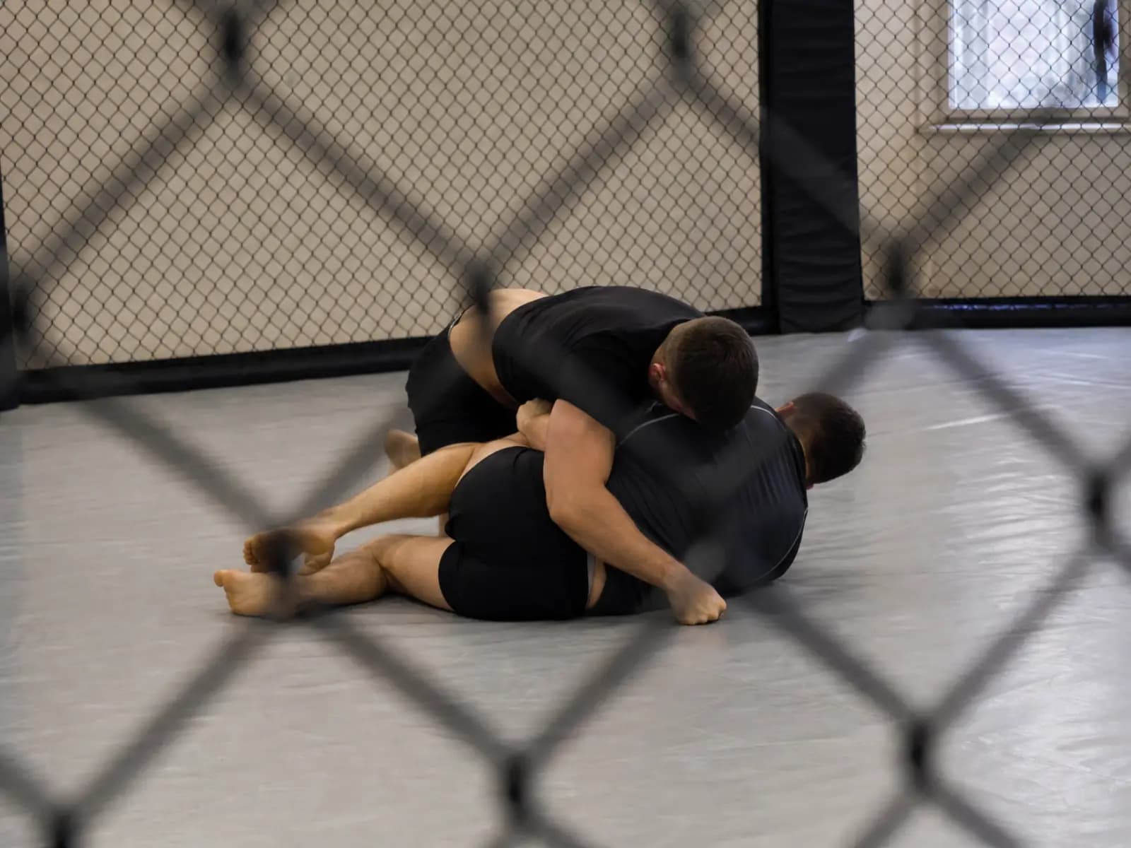Dwie osoby trenują sparing chwytany na macie MMA