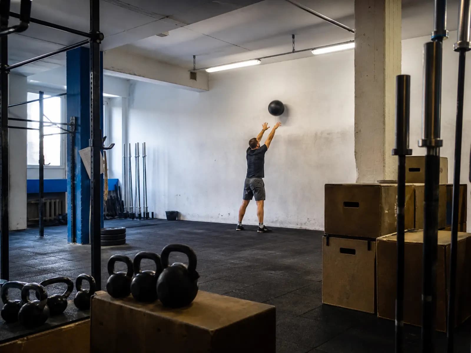 Osoba rzuca piłką lekarską o ścianę w boksie crossfitowym