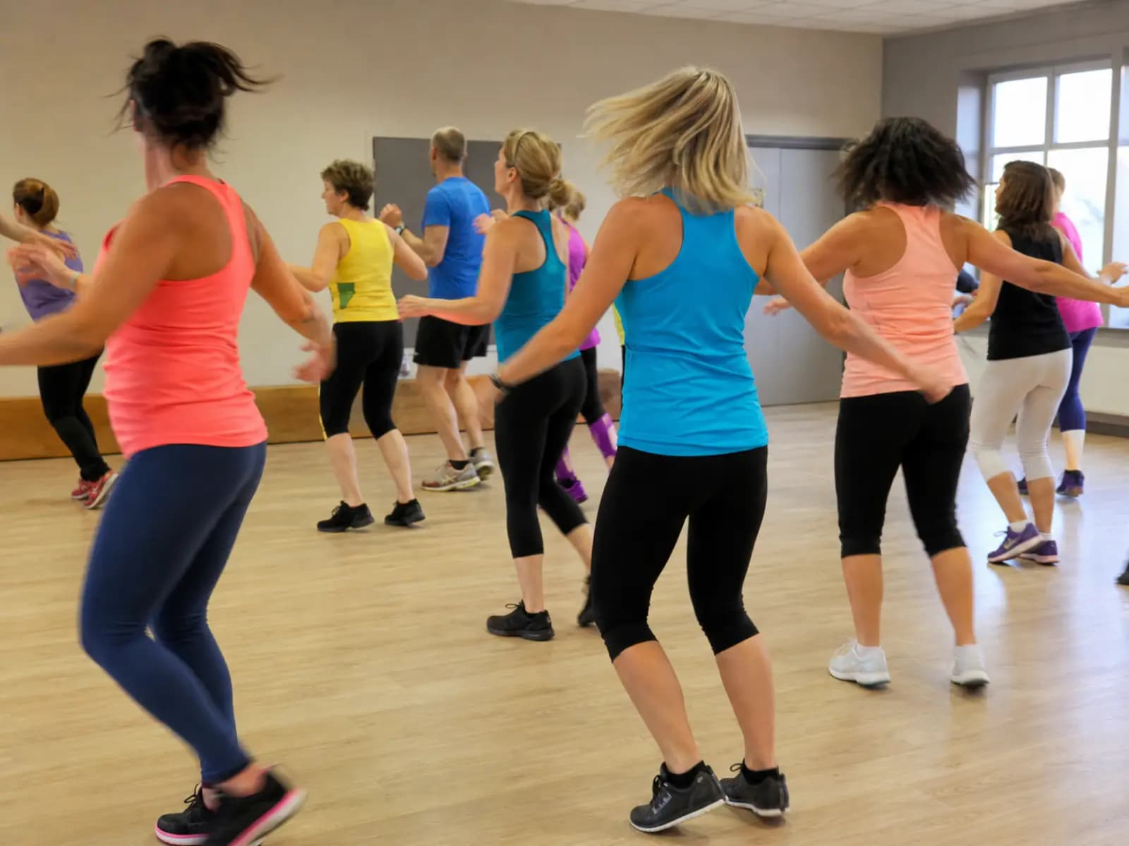 Grupa tańczy zumbę podczas zajęć w sali fitness